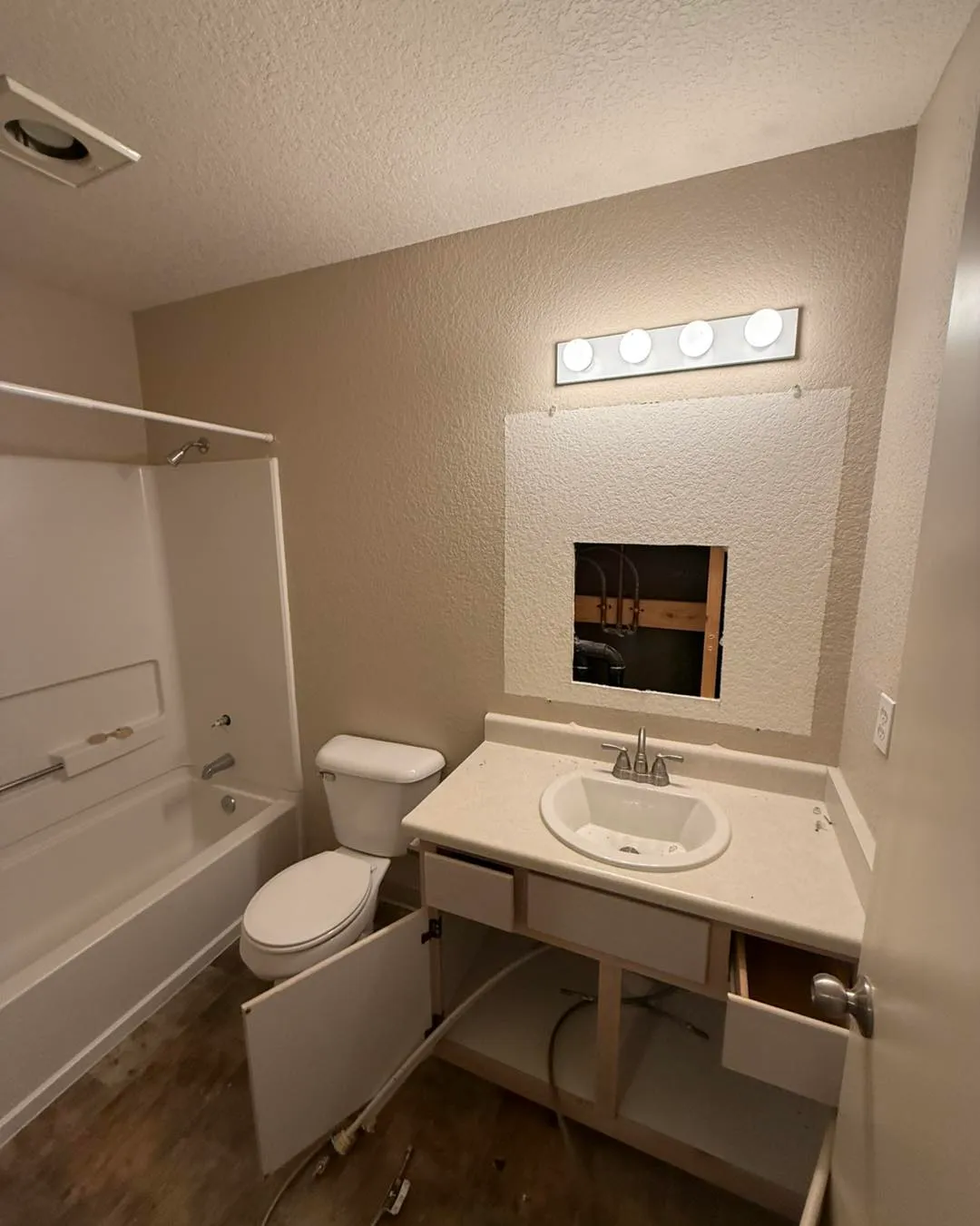 Bathroom wall cut open behind vanity exposing plumbing rough-in and copper-to-PEX transition