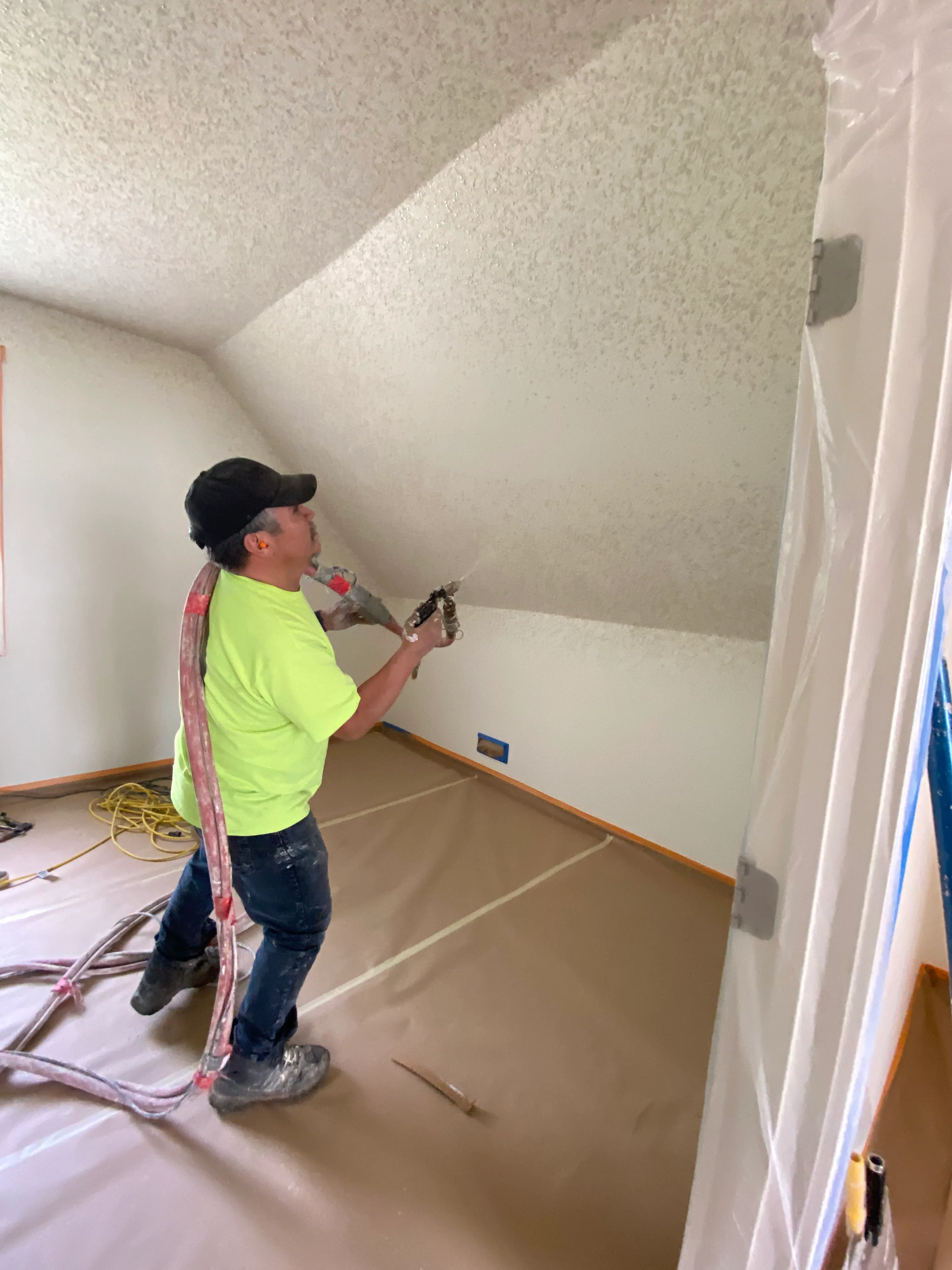 Drywall crew spraying wall texture in a new construction home