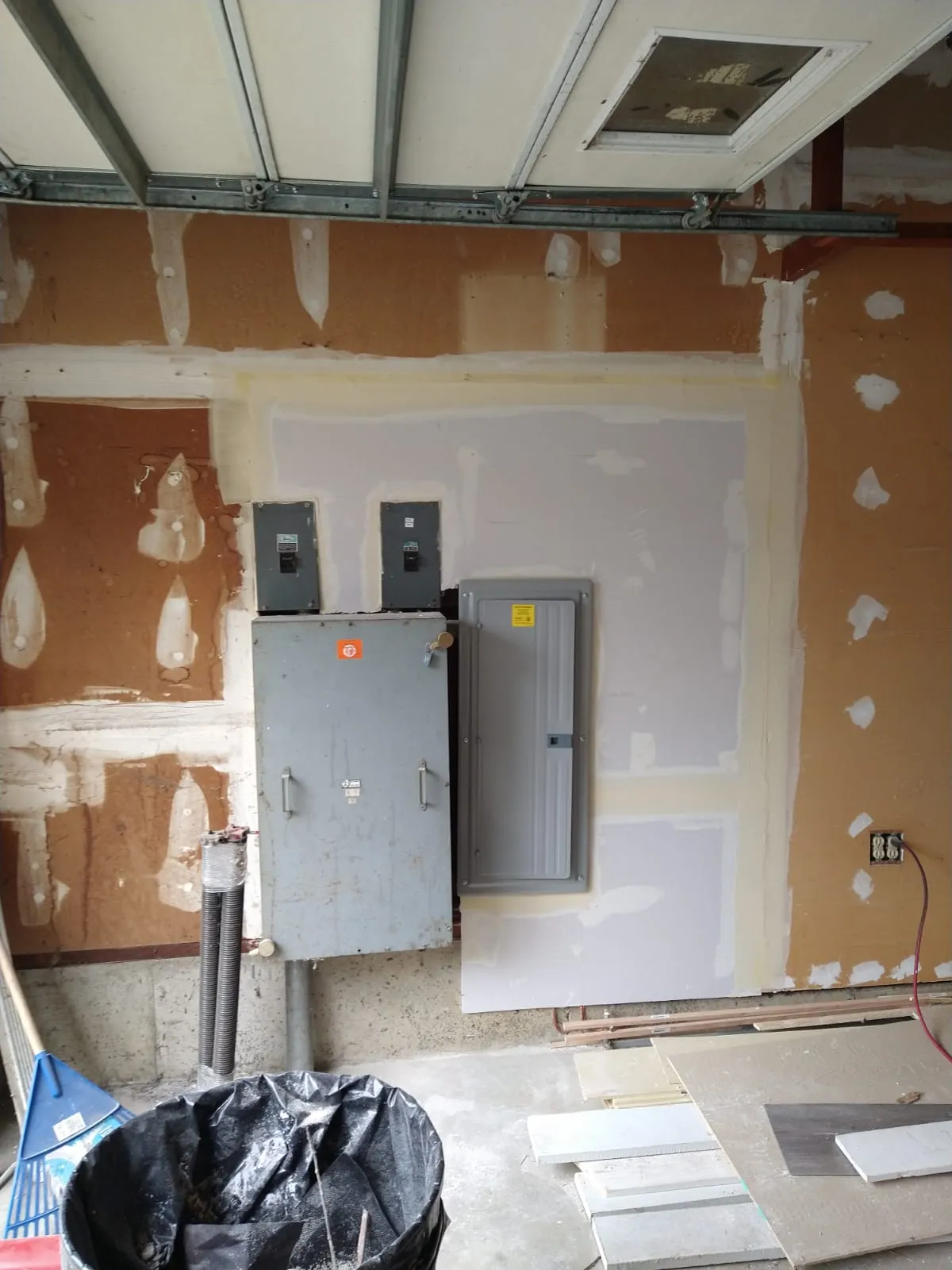 Drywall patch in progress with new board and joint compound around an electrical panel