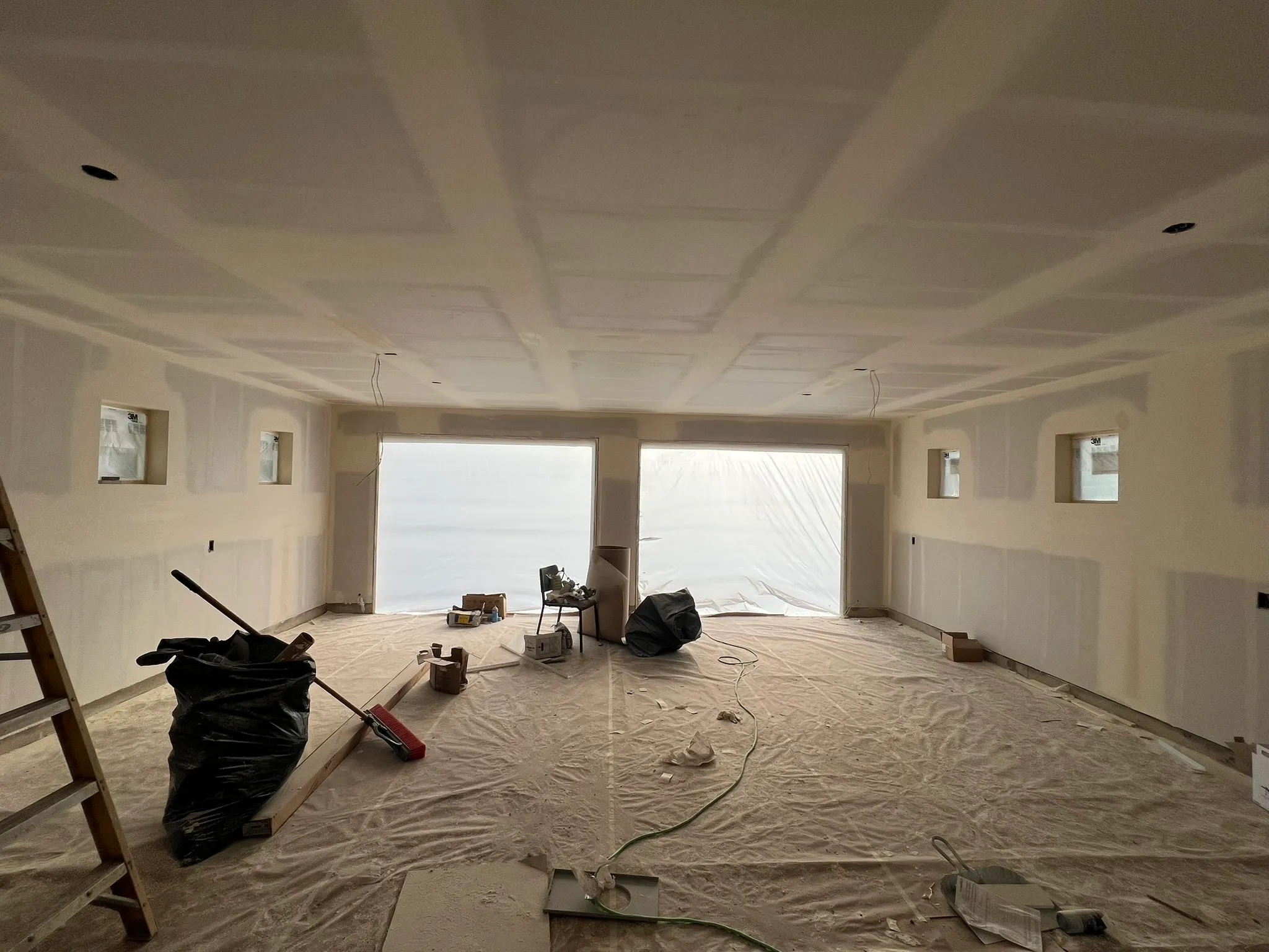 AvilaCo crew member taping and mudding drywall seams in a new construction room