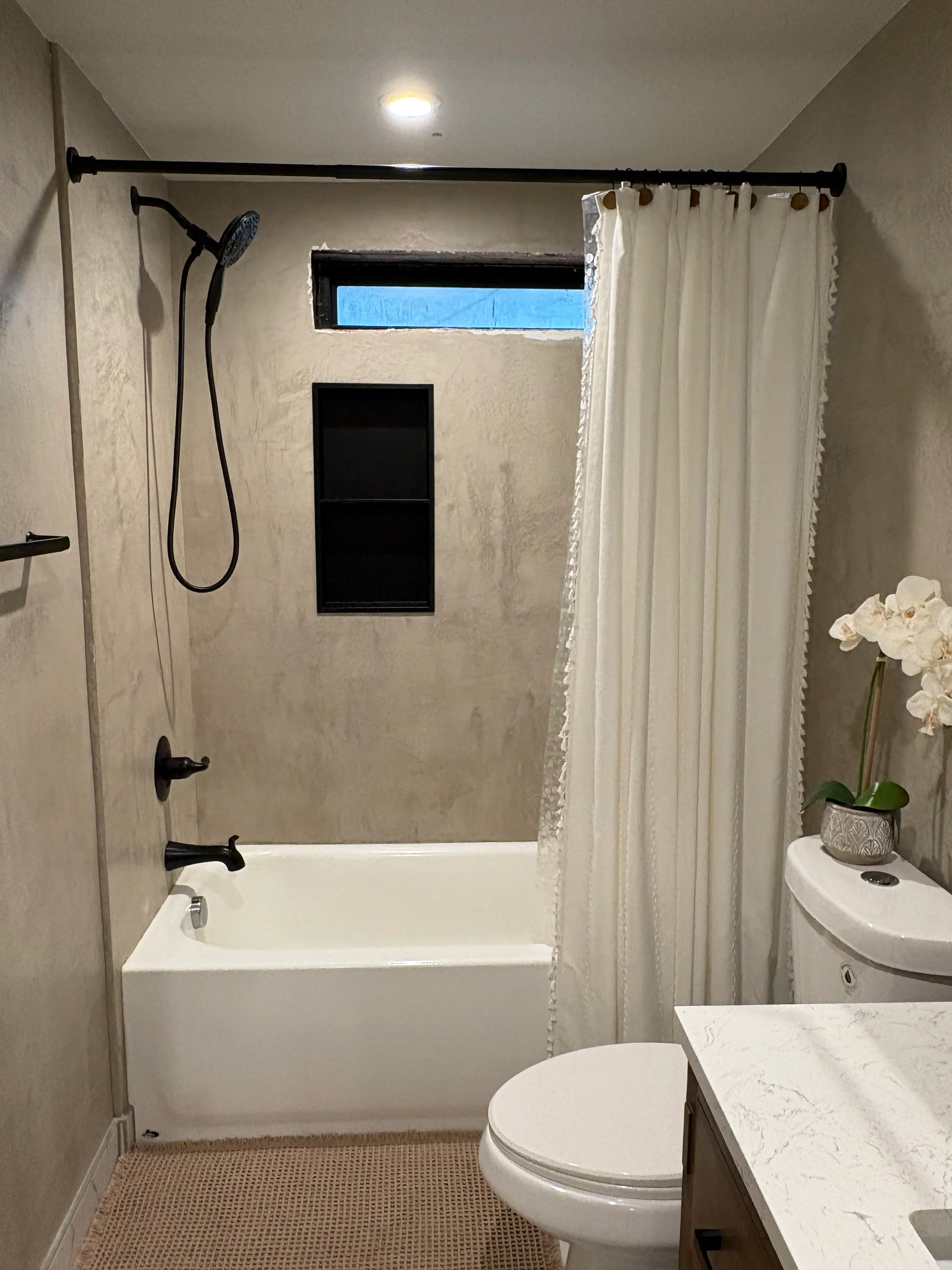 Decorative plaster shower surround with built-in niche applied over existing tile in Clark County WA